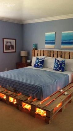 a bed made out of wooden pallets with candles on each side and two pictures above it