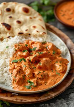 a plate filled with rice and meat next to naan bread on a wooden platter