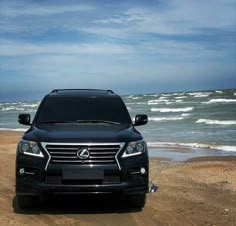 a black suv parked on the beach next to the ocean