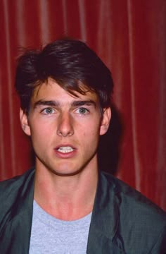 a young man is posing for a photo in front of a red curtain with his mouth open