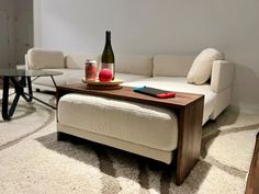 a bottle of wine sitting on top of a wooden table next to a white couch