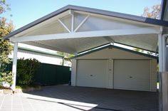 a white carport in the middle of a driveway with two garage doors on each side