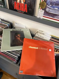 an orange vinyl album sitting on top of a book shelf filled with cds and records