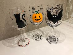 three wine glasses decorated to look like halloween cats and pumpkins with black dots on them