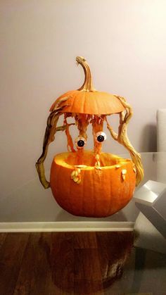 a carved pumpkin with googly eyes and branches sticking out of it's mouth