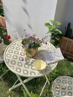 a small table and chairs with flowers in the potted planter next to it