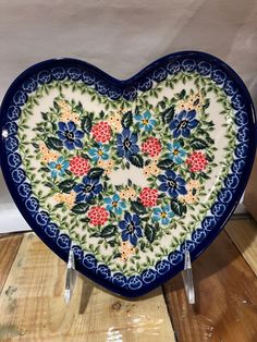 a blue and white heart shaped plate with flowers on it sitting on a wooden table