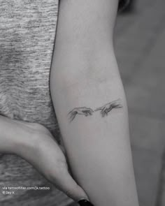 a woman's arm with two birds on it and one is holding the other