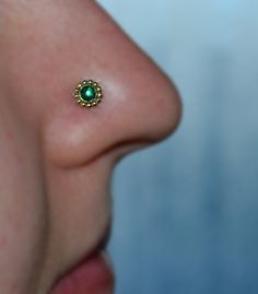 a woman's nose with a green jeweled nose piece on it, and the tip of her nose is visible