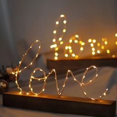 the word love is made out of string lights on a wooden stand next to other decorations