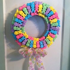 a colorful wreath with teddy bears on it hanging from the front door, decorated with ribbon