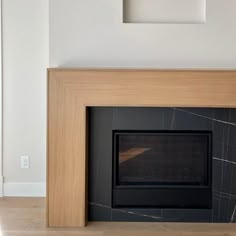 an empty room with a fireplace in the center and a framed photograph on the wall