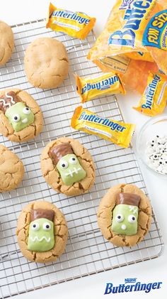 cookies with green frosting and googly eyes are on a cooling rack next to some candy