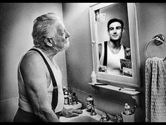 an old man standing in front of a bathroom sink looking at himself in the mirror