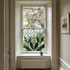 a stained glass window in the corner of a room with wood flooring and white walls