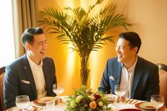 two men sitting at a dinner table laughing