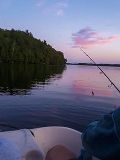 a person is fishing on the water at sunset or dawn with their boat in the foreground