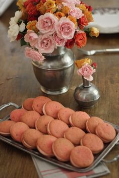 there are many small cookies on the table with flowers in the vases behind them