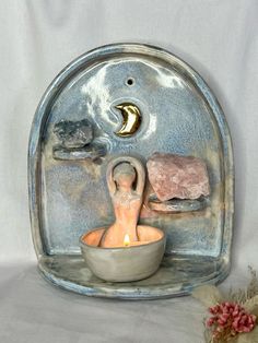 there is a small bowl with a candle in it and some rocks on the side