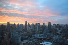 the city skyline is lit up at sunset with pink clouds in the sky and buildings below