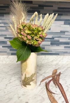 a vase filled with lots of flowers on top of a counter next to a snake