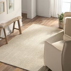 a living room with white walls and wooden flooring next to a beige rug on the floor