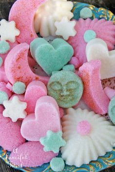 pink, blue and green heart shaped cookies on a plate with seashells in the background