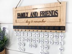 a family and friends sign hanging on a wall next to a potted plant with flowers