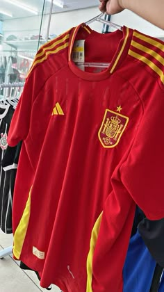 several soccer jerseys are on display in a store, one is red and the other is yellow