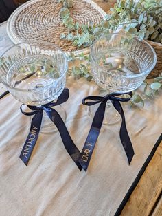 two clear glass bowls with blue ribbons on top of a table next to a wicker basket