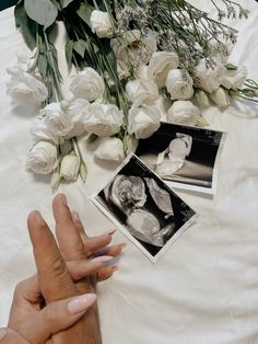 two hands touching each other on a table with flowers and pictures next to it,