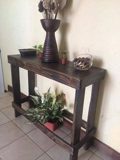 a wooden table with some plants on it and a vase full of flowers sitting on top