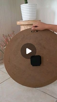 a person holding up a large wooden object in the middle of a room with white walls