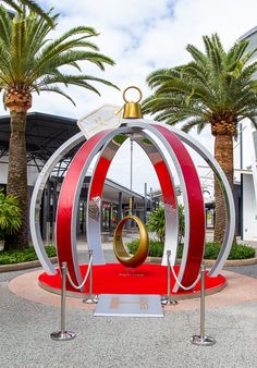 a large metal sculpture in the middle of a street with palm trees around it and a red carpet