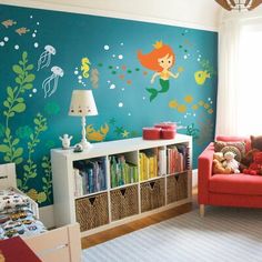 a child's room decorated in blue and green with little mermaids on the wall