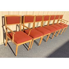 a row of red chairs sitting next to each other on top of a cement floor