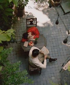 two people sitting at an outdoor table reading