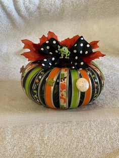 an orange striped pumpkin with black and white polka dots on it's top sitting on a white surface