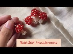 someone is making beaded mushrooms with red and white beads on their thumbnails