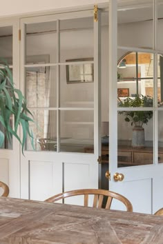 a wooden table sitting in front of a white door with glass panels on the side