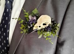 a man in a suit with a skull and flowers on his lapel