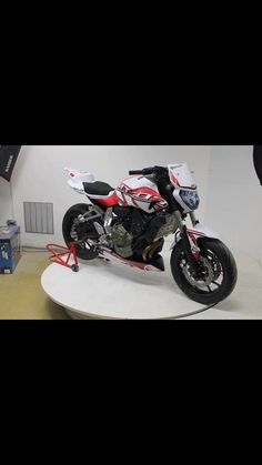 a red and white motorcycle on display in a room with other items around the room