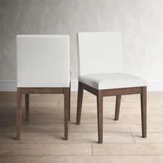 two white chairs sitting next to each other on a wooden floor