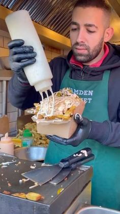 a man in an apron is pouring something into a container