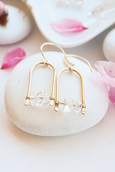 These earrings are excellent for a sparkle in the sunlight, with a warm sunny golden glow. They feature stunning herkimer diamonds across the bottom of an open geometric frame. They're hand hammered at the bottom of the frame and they make a cute and dainty match for professional, sexy, and casual outfits. Available in gold, rose gold, and silver, they're the perfect dangles for any style. Wire Wrapped Crystal Earrings For Jewelry Making, Minimalist Wire Wrapped Crystal Earrings As Gift, Minimalist Wire Wrapped Crystal Dangle Earrings, Earring Making Ideas, Elegant Gold Wire Wrapped Crystal Earrings, Wire Wrapped Brass Crystal Drop Earrings, Diy Wire Earrings, Silversmithing Jewelry, Casual Earrings