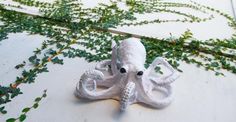 an octopus figurine sitting on top of a white table next to ivy covered walls