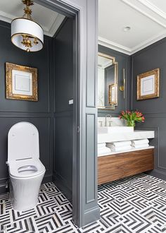 a white toilet sitting next to a sink in a bathroom under a mirror on top of a wall