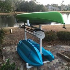 a green and blue boat sitting on top of a brick walkway next to a lake