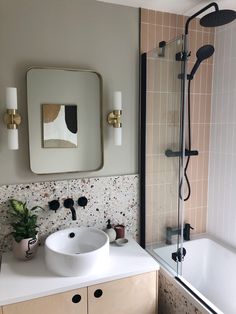 a white sink sitting under a bathroom mirror next to a bath tub and shower head