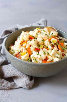 a bowl filled with cauliflower and carrots on top of a gray table